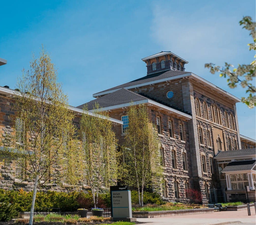 Exterior image of Waypoint's Atrium Building with budding trees surrounding it.