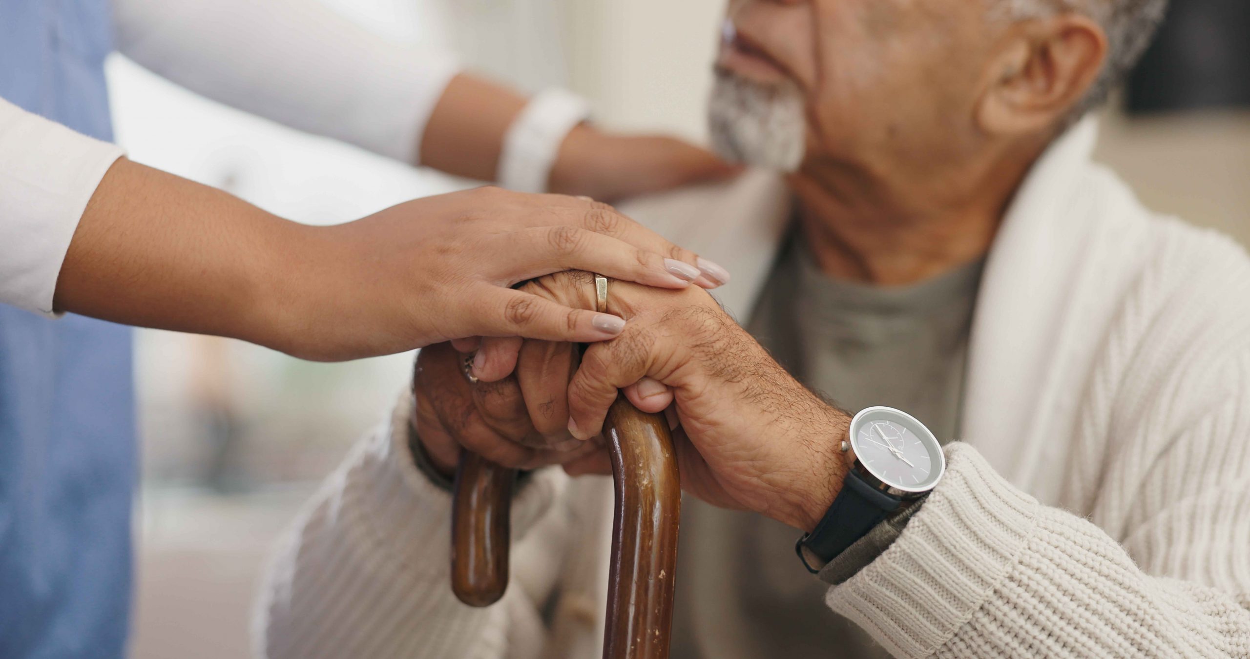A caregiver assisting senior with a walking stick, offering support and empathy.