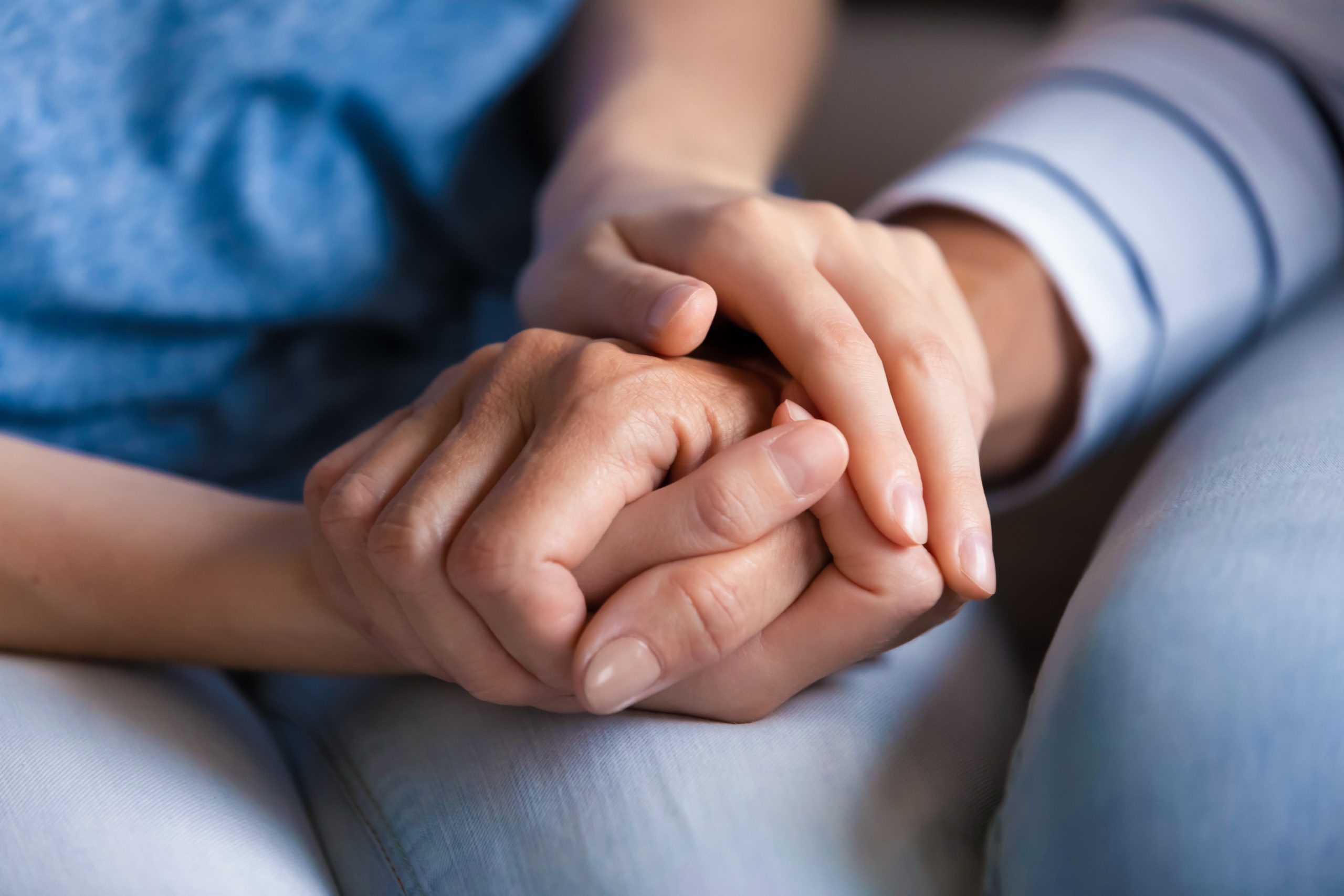 A supportive loved on holds a patient's hand.