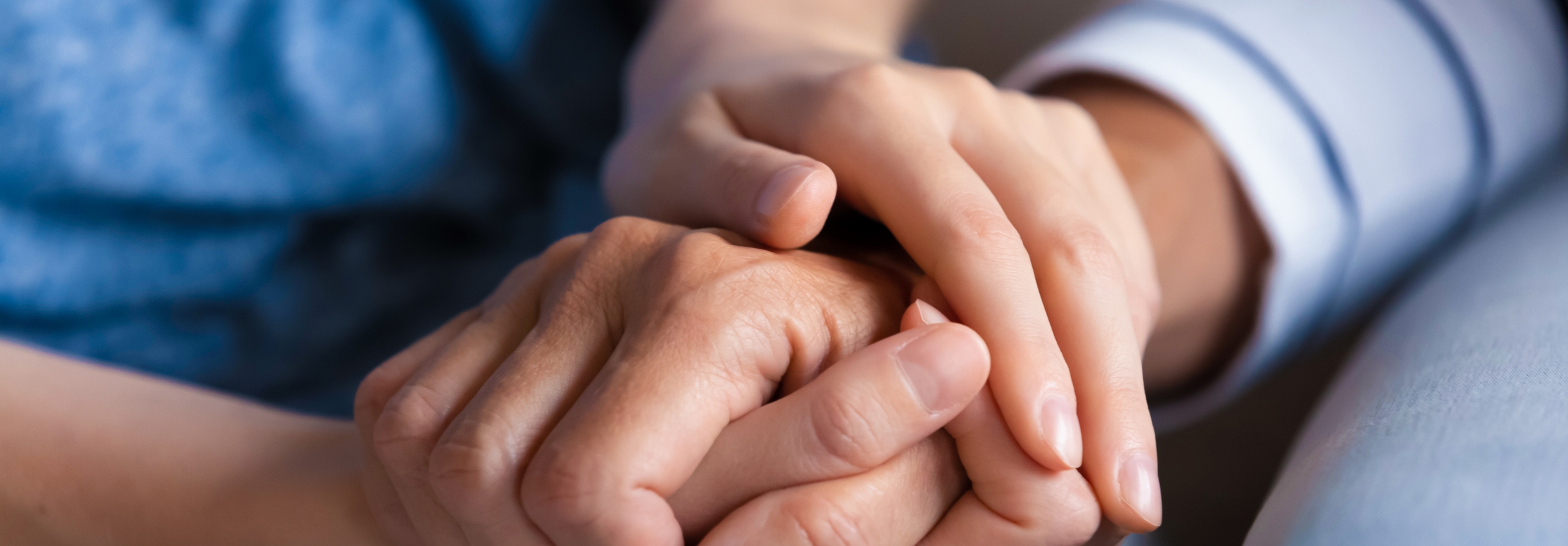 A supportive loved one holds a patient's hand.