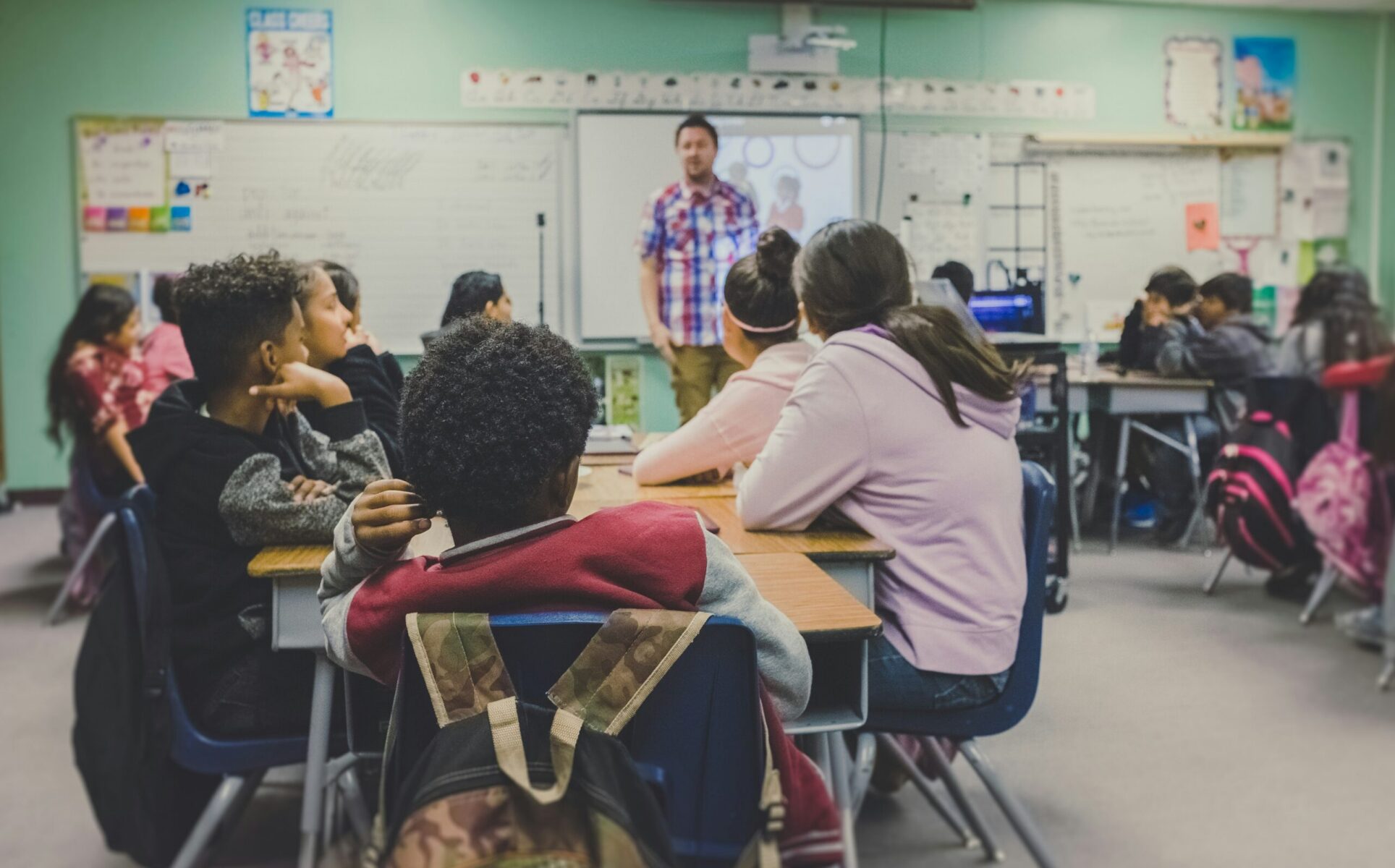 Students in a classroom listening to a teacher