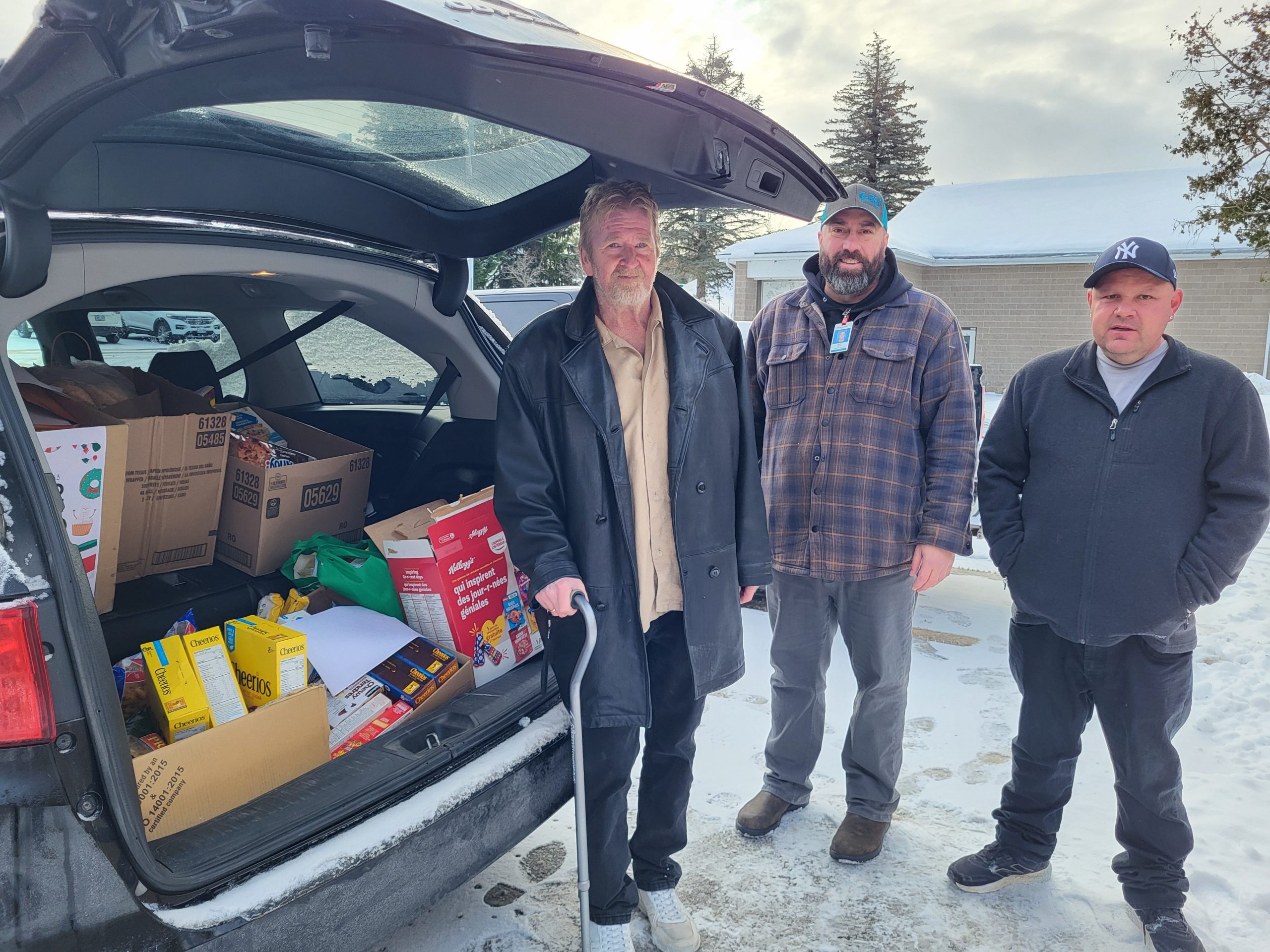Patients in front of an open car full of food