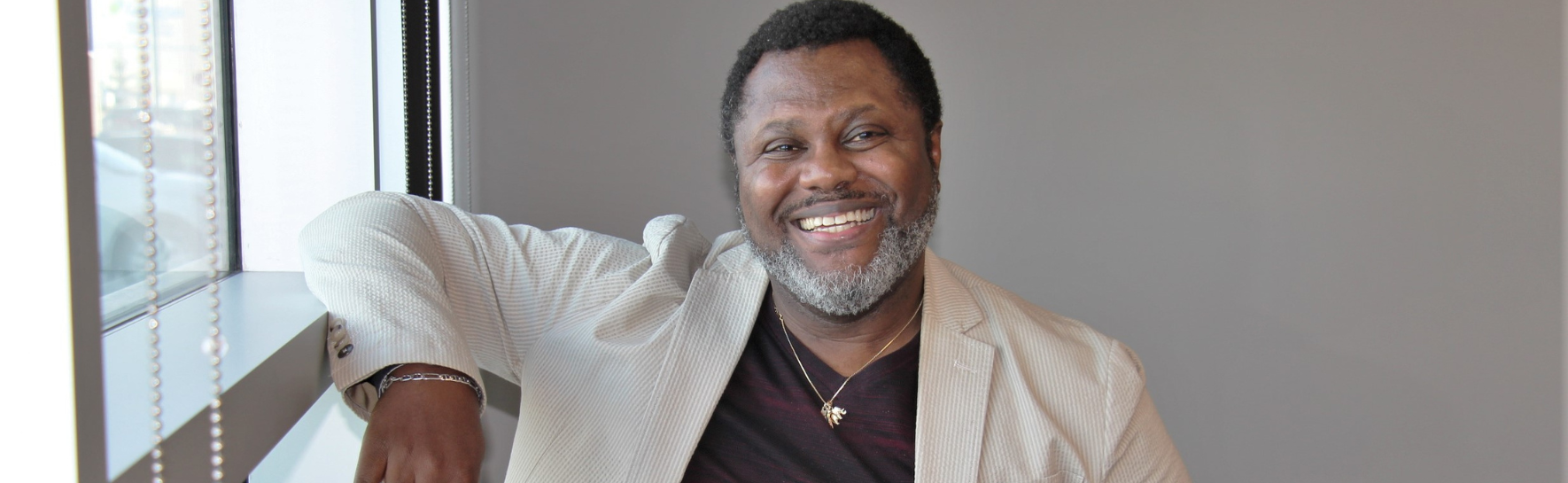 Dike Onuaha standing in front of a window smiling