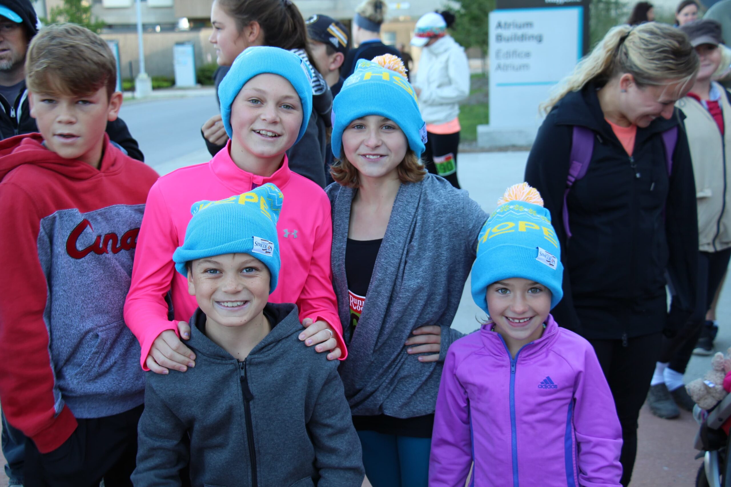 Five children posing with blue beanie hats that say HOPE.