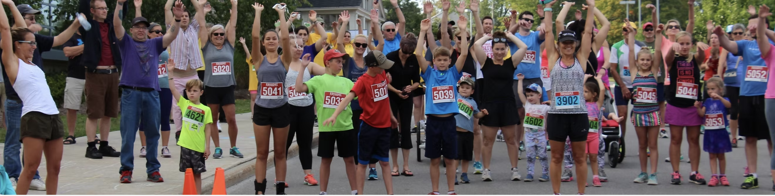 A group of runners at a race, with arms held up in the air as if celebrating.