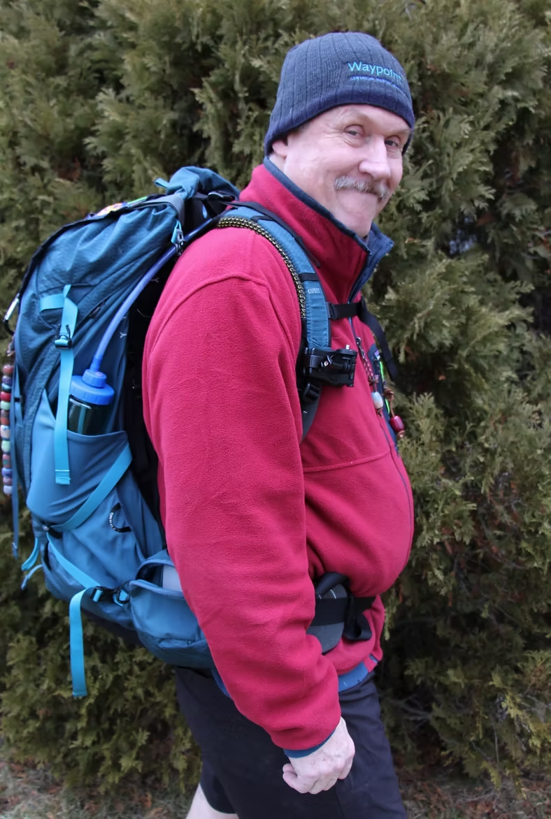 Steve Parry wearing a hiking backpack, smiling at the camera.