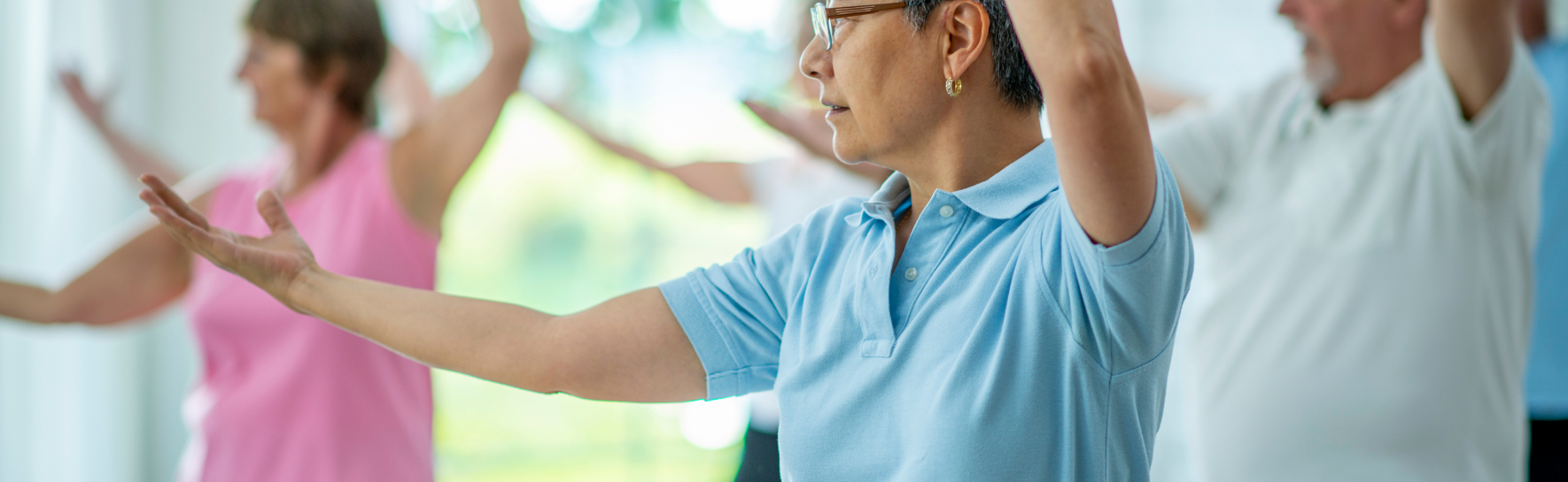 A woman practicing tai chi in a blue shirt