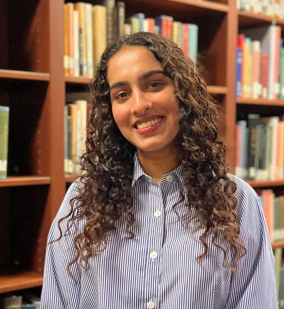 Prisha standing in front of a bookcase