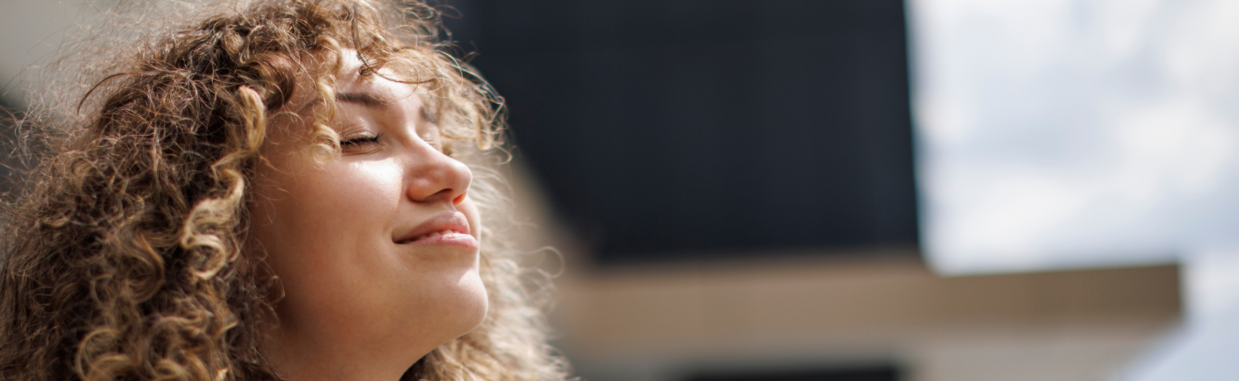 A woman looks into the sun with a glowing smile