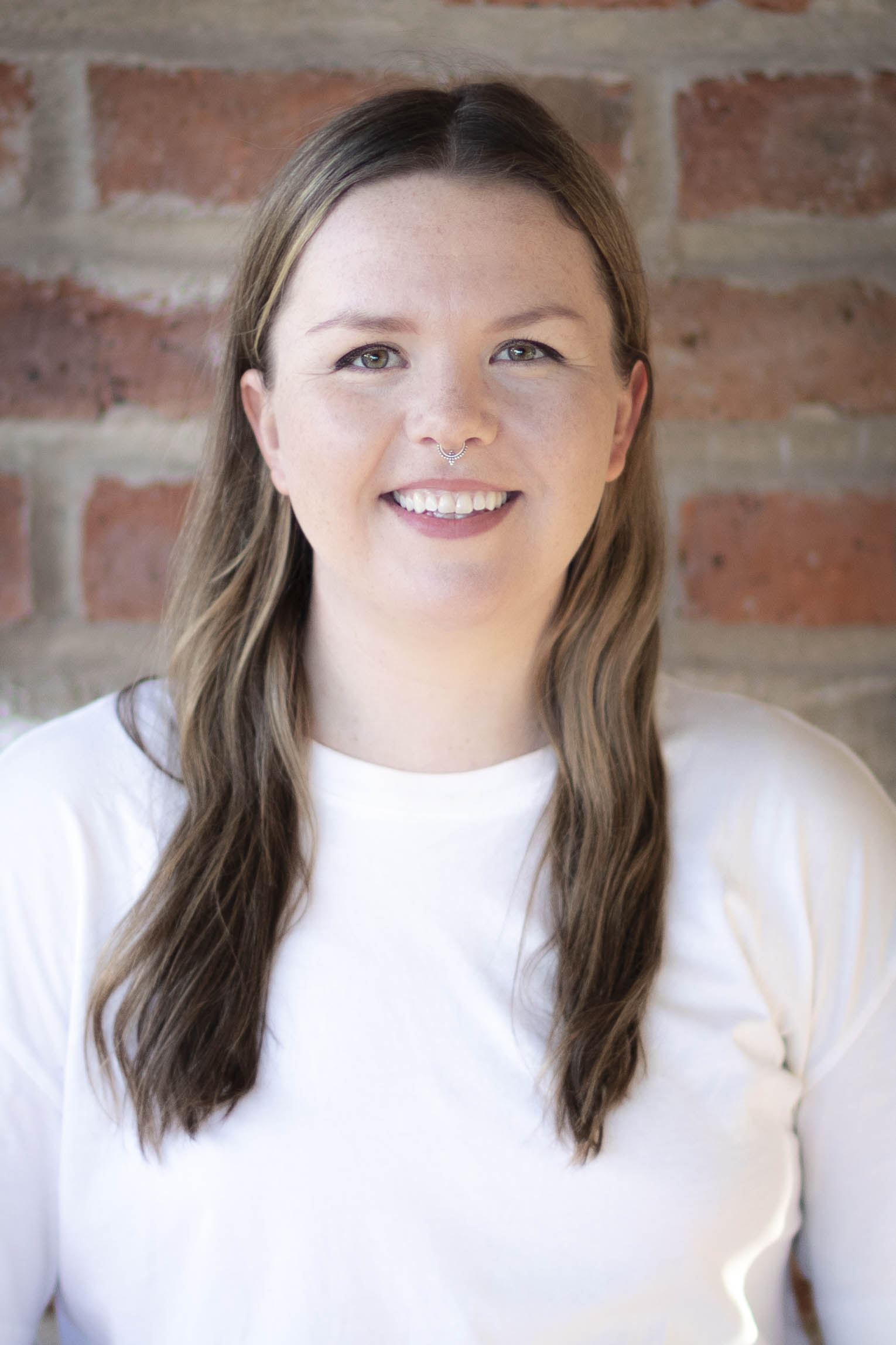 Zoe smiling standing in front of brick wall